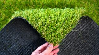 Hand folding down the corner of a piece of artificial grass